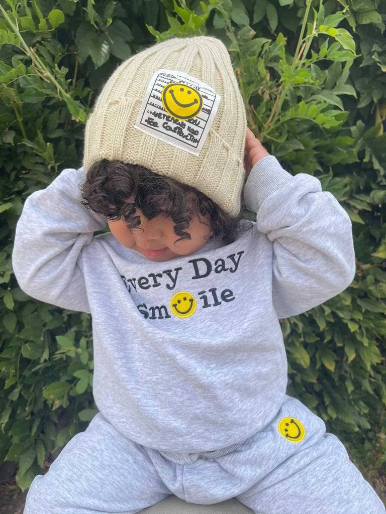 Baby boy wearing a smiley face ribbed beanie and smiley sweatshirt matching set